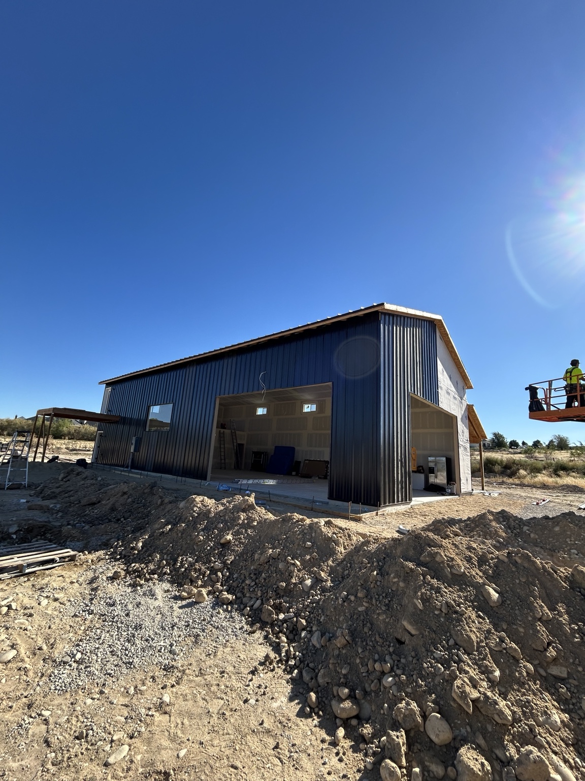Overall view of the black metal shop with PBR siding installation in progress